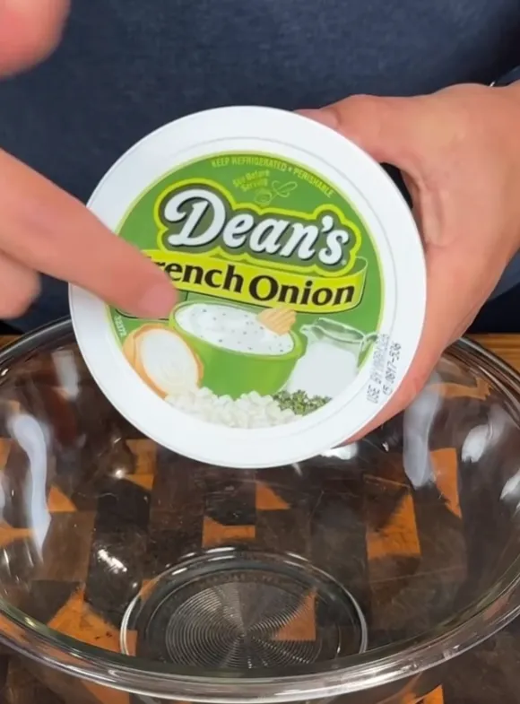 A tub of Dean's French onion dip being added to a bowl