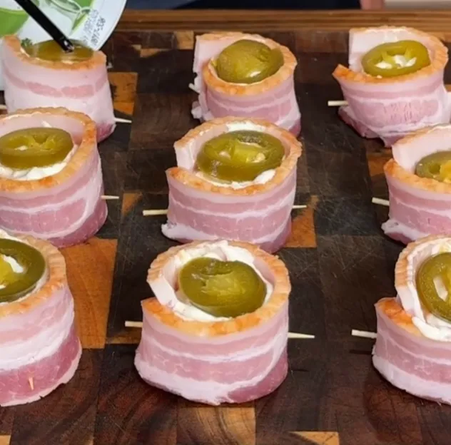 Pickled jalapeño slices being placed on top of the filled bacon cups
