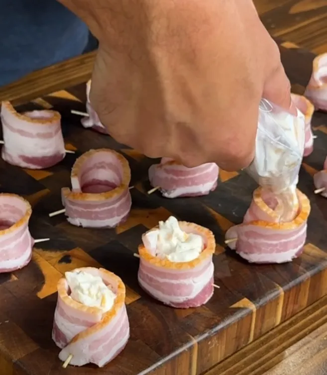 Cheese filling being piped into the bacon-wrapped sausage cups