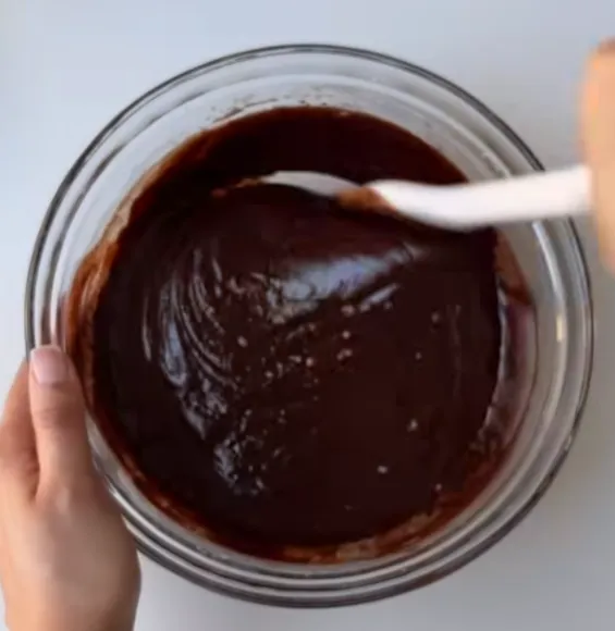 Glossy fudgy brownie batter in a glass bowl