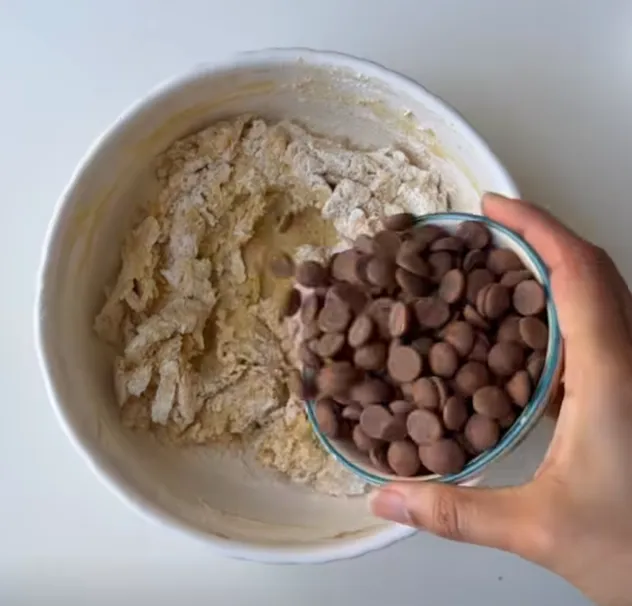 Chocolate chips being folded into chocolate chip cookie dough