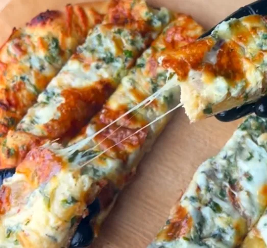 Cheesy garlic bread cut into strips and pulled apart to show the stretchy cheese