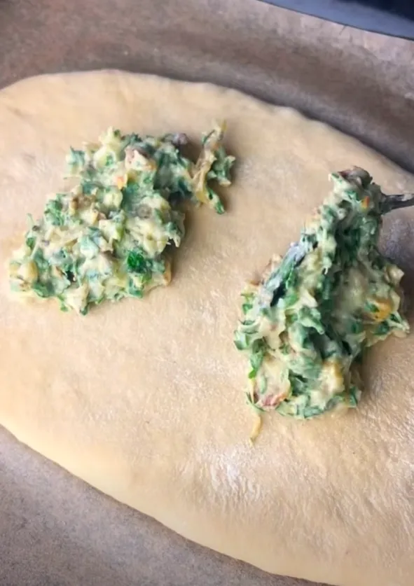 Garlic herb butter being spread over the shaped dough