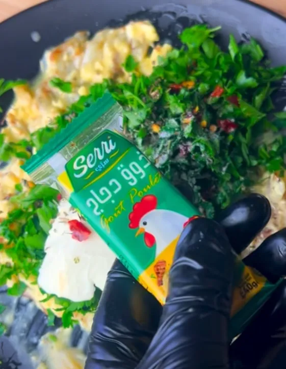 A crumbled stock cube being added to the garlic herb butter