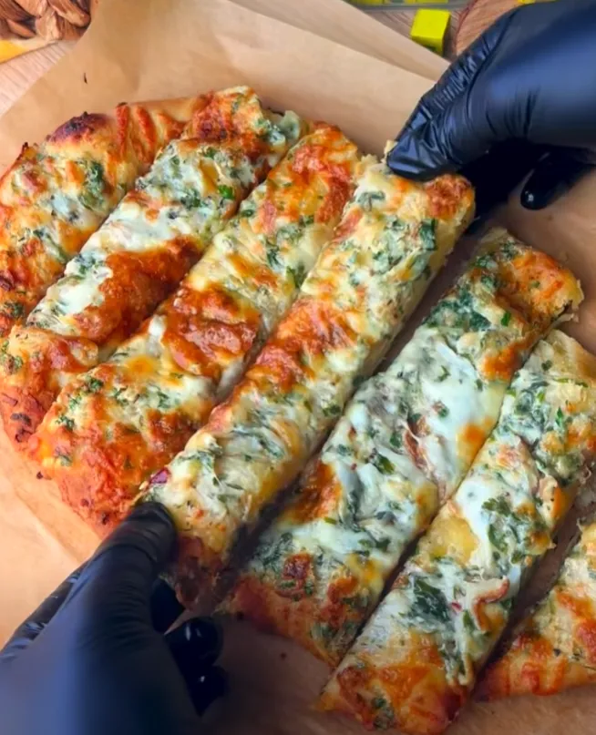 Cheesy garlic bread sliced into strips on a wooden board