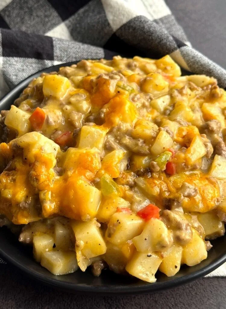 Cheesy ground beef and potato casserole served in a black bowl
