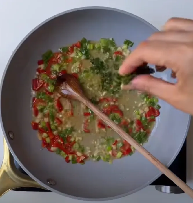 Garlic, red chilli, bell pepper and green onion frying in oil