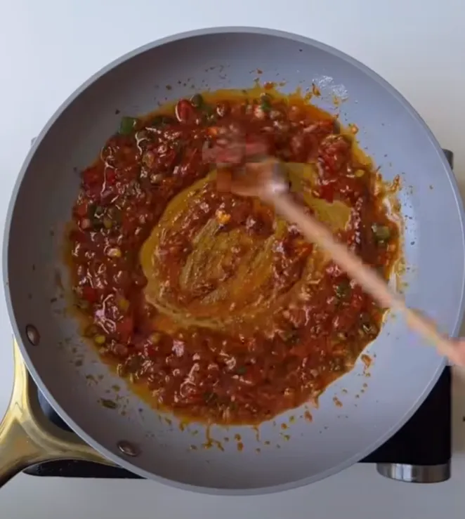 A thick deep-red chili garlic sauce simmering in the pan