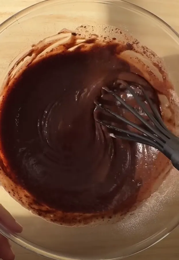 Smooth, glossy chocolate cake batter in a glass bowl