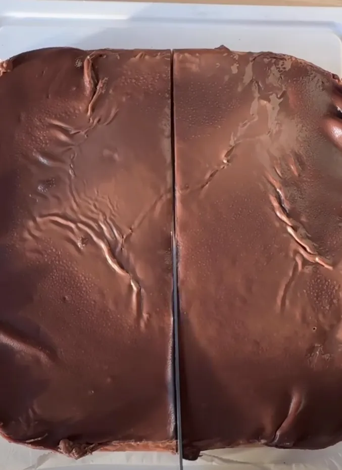 The set chocolate slab being cut into bars with a knife