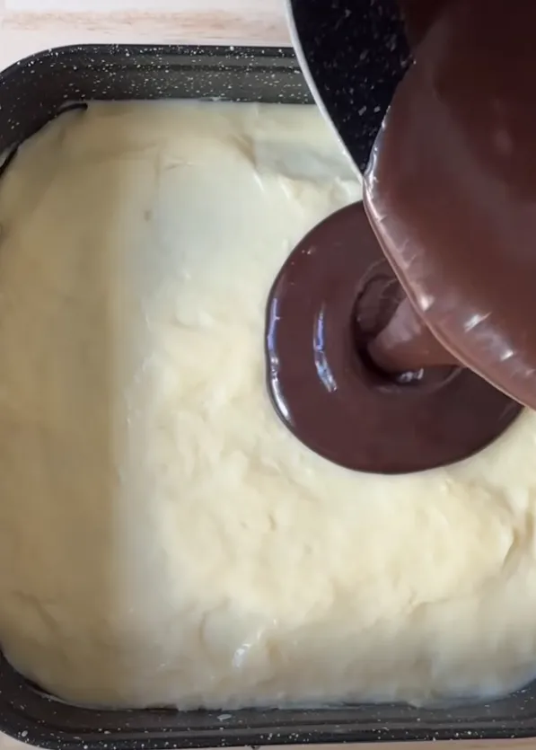 Chocolate ganache being poured over the milk cream layer