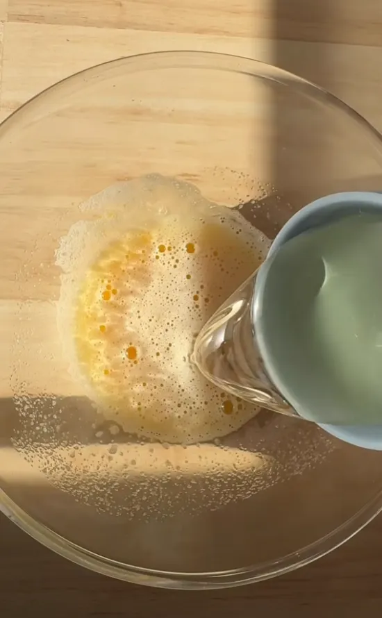 Vegetable oil being poured into the whisked eggs and sugar
