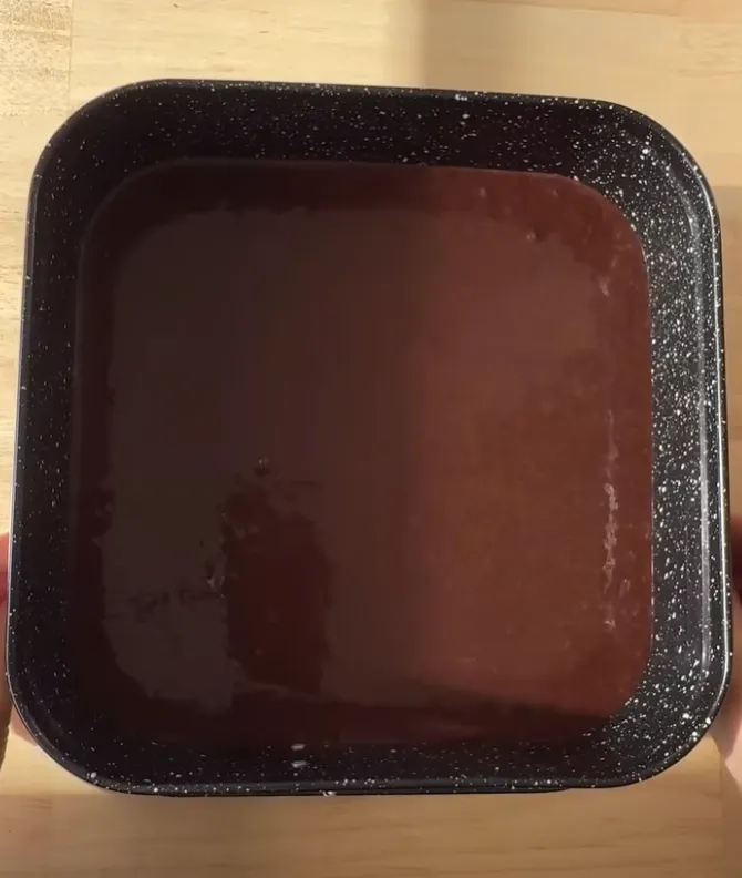 Chocolate cake batter poured into a square baking tin