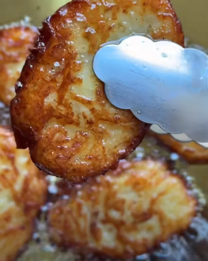 Golden garlic parmesan hashbrowns frying and being lifted from hot oil
