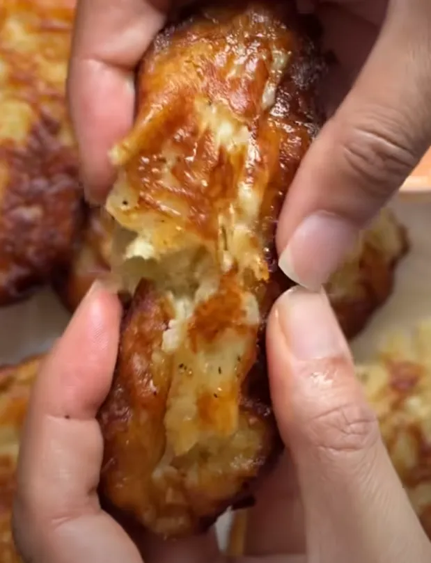 A garlic parmesan hashbrown torn open to show the soft, fluffy potato inside