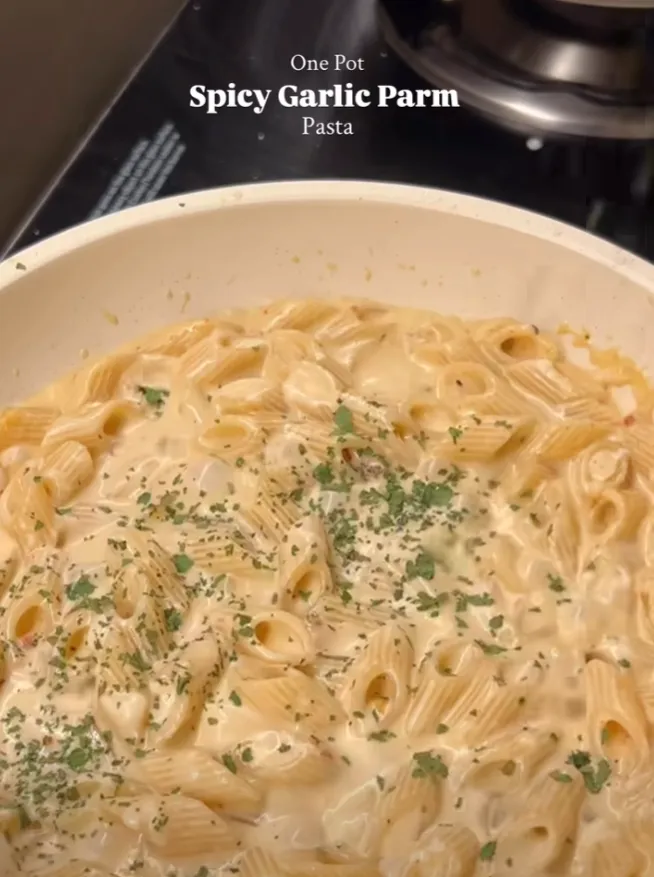 A top-down pan of creamy one pot spicy garlic parmesan penne pasta scattered with parsley