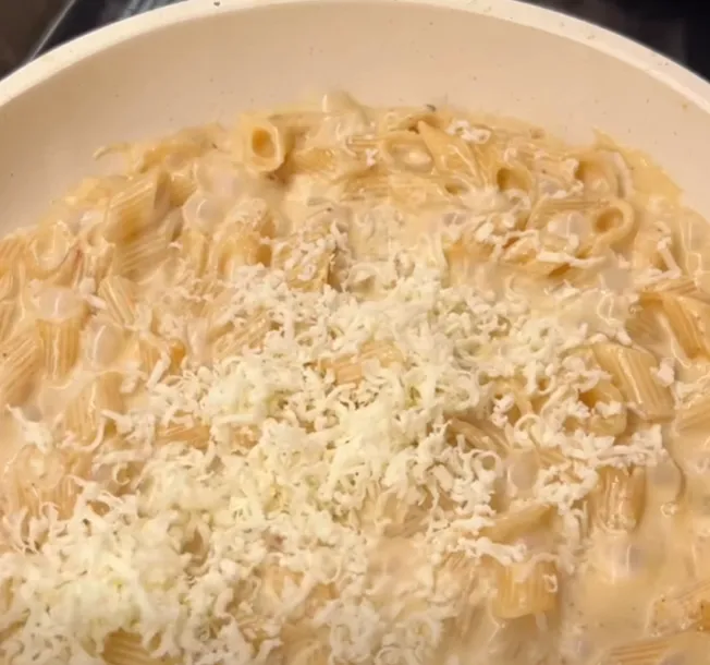 Grated parmesan scattered over the creamy penne and stirred into the sauce