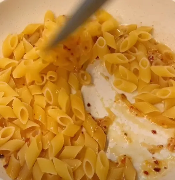 Dry penne added to the pan and tossed in the spicy garlic butter