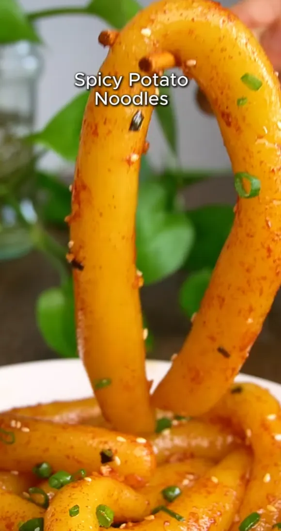 A single chewy potato noodle lifted up to show its stretchy, bouncy texture