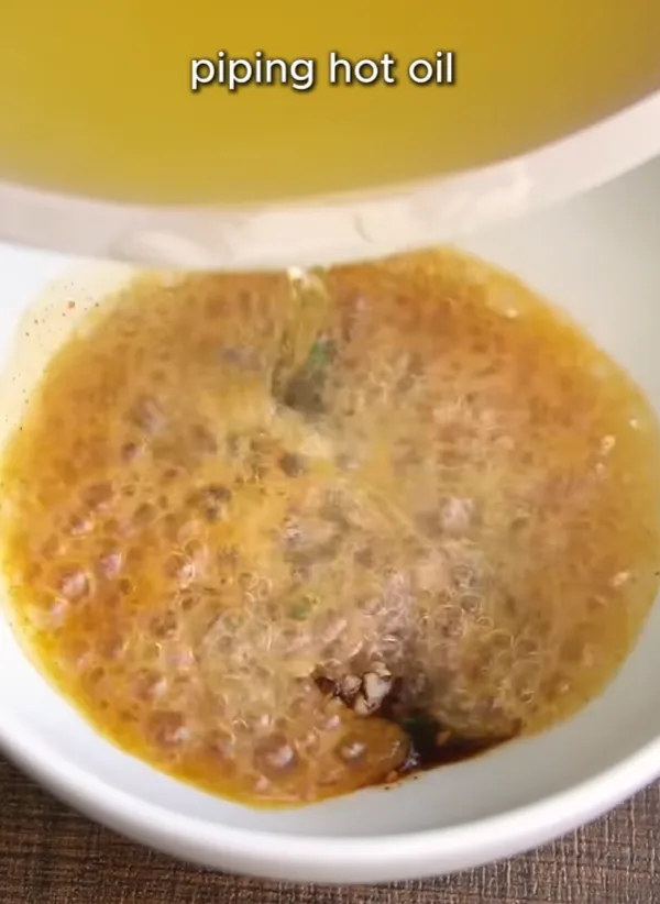 Smoking-hot oil being poured over the chili and garlic sauce mix, sizzling