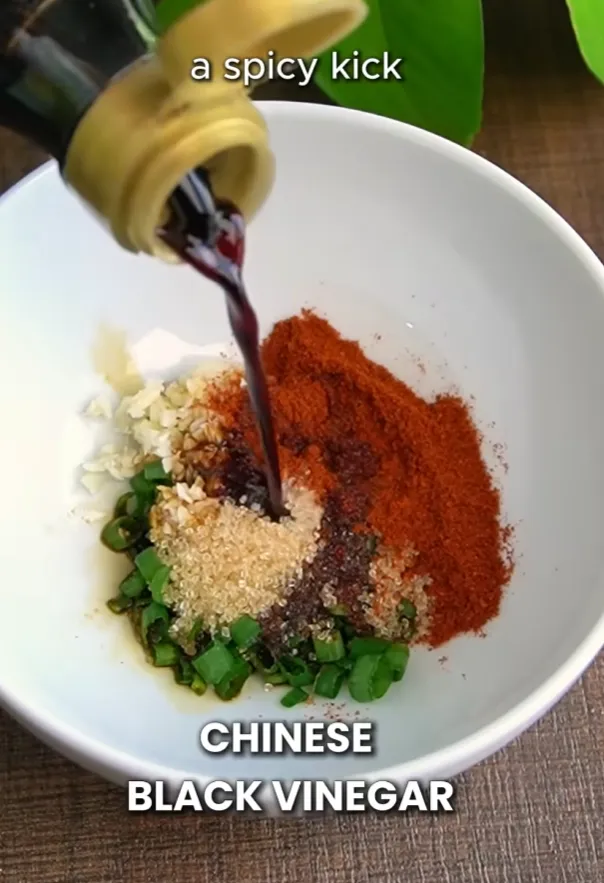 A bowl of sauce ingredients — garlic, spring onion, chili powder, sugar and black vinegar