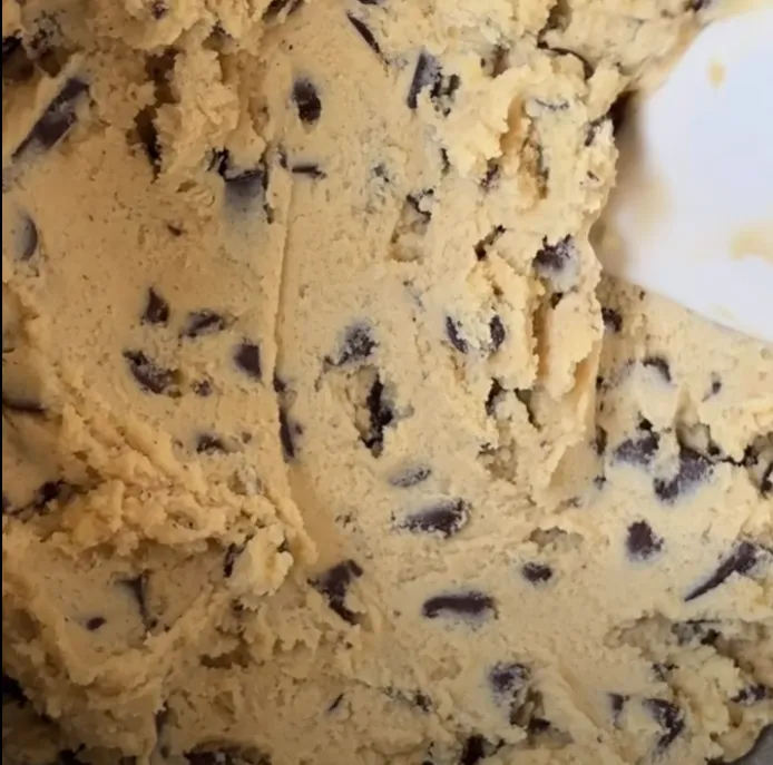 A close-up of thick chocolate chip cookie dough loaded with chocolate