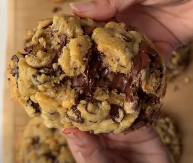 A warm thick chocolate chip cookie pulled apart to show melting chocolate inside